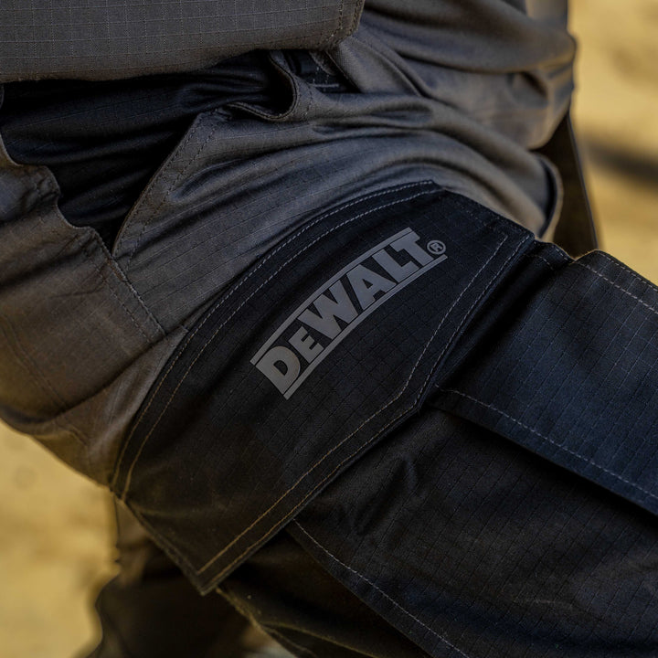 Close-up of dark pants with a Dewalt logo on a blurred background