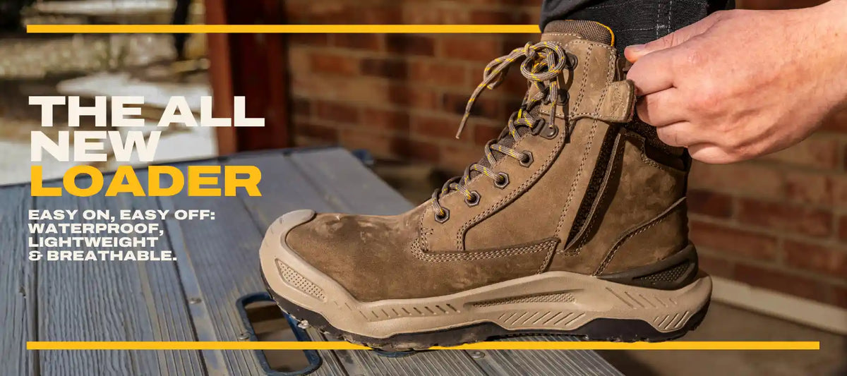 A person's hand adjusting the strap of a brown suede hiking boot resting on a wooden surface, with a brick wall in the background. Promotional text on the left reads 'THE ALL NEW LOADER' and highlights waterproof, lightweight, and breathable features.