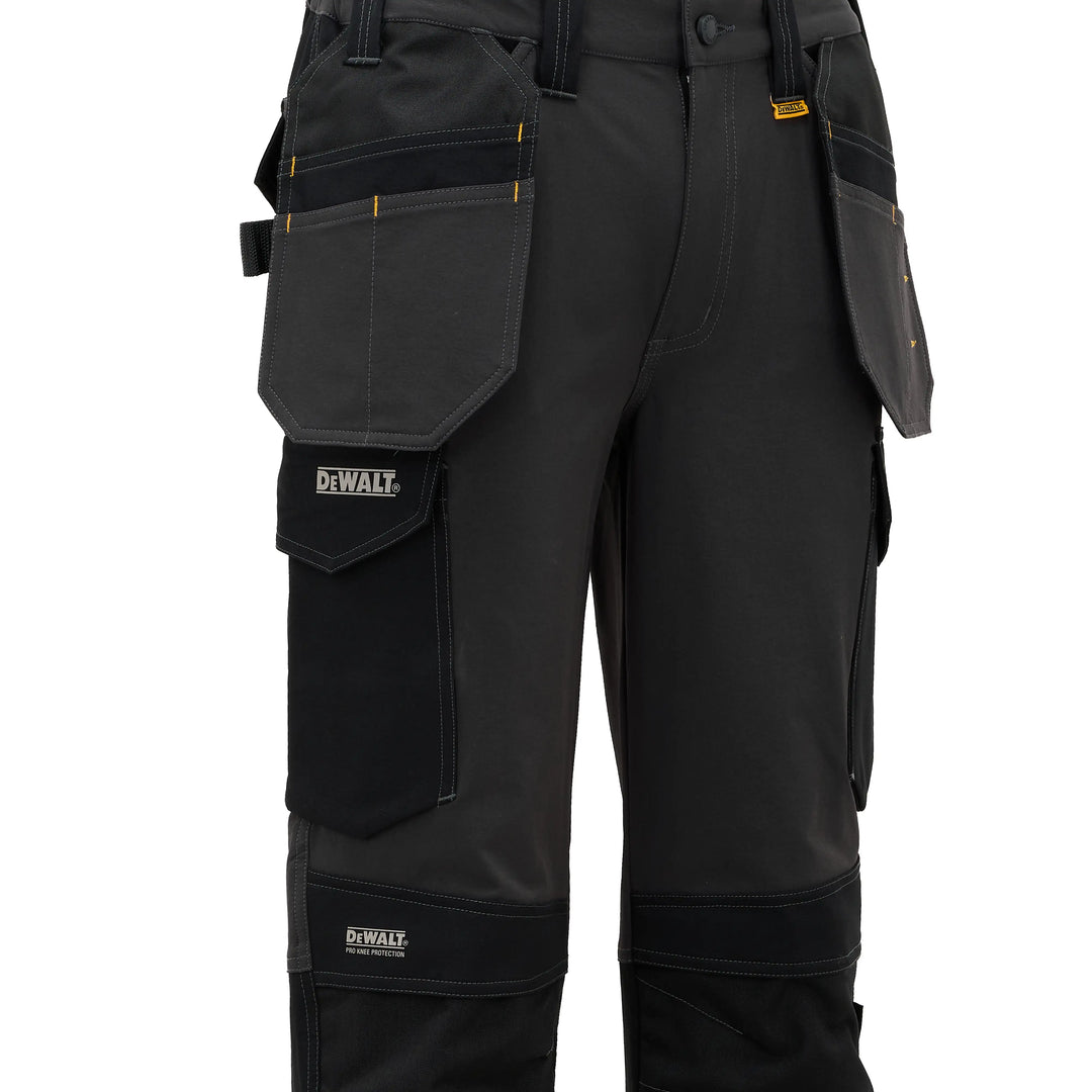 Black DeWalt work pants with multiple utility pockets, reinforced knee and ankle panels, and yellow brand accents, shown on a white background.