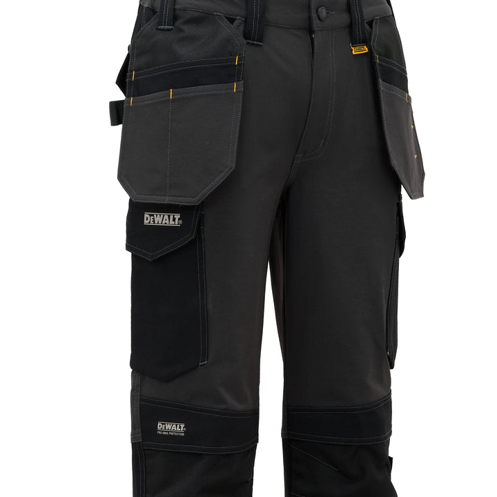 Black DeWalt work pants with multiple utility pockets, reinforced knee and ankle panels, and yellow brand accents, shown on a white background.