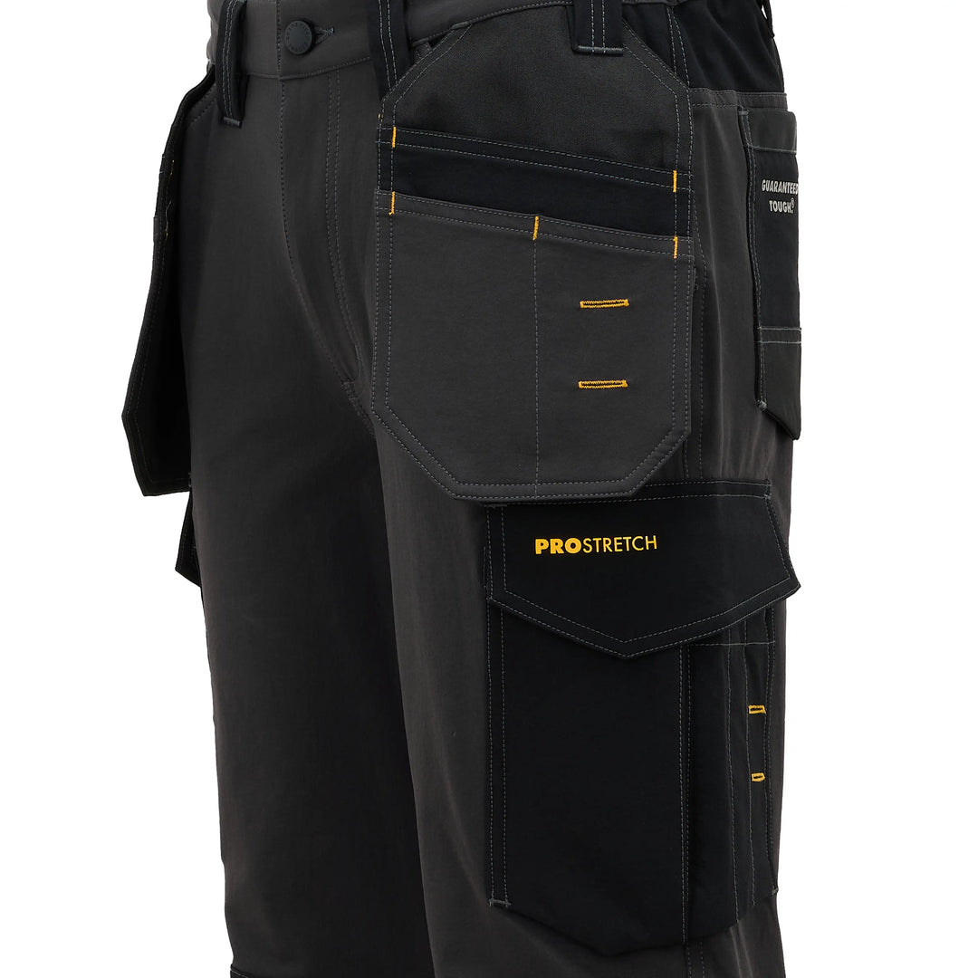 Close-up of black work pants with multiple utility pockets, yellow contrast stitching, and a visible PROSTRETCH logo on a pocket flap, shown against a plain white background.