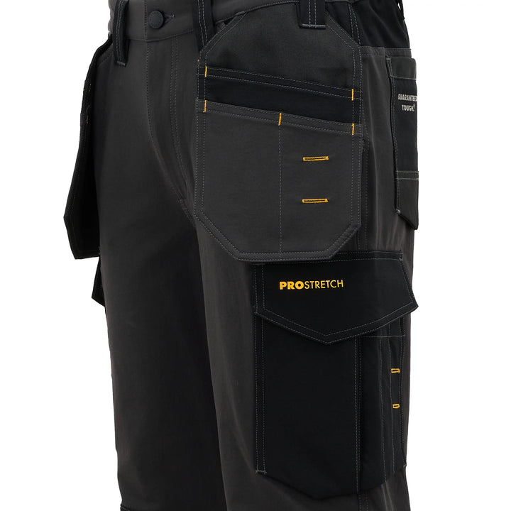 Close-up of black work pants with multiple utility pockets, yellow contrast stitching, and a visible PROSTRETCH logo on a pocket flap, shown against a plain white background.