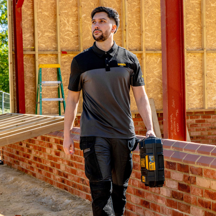 Man in work attire holding a toolbox on a construction site