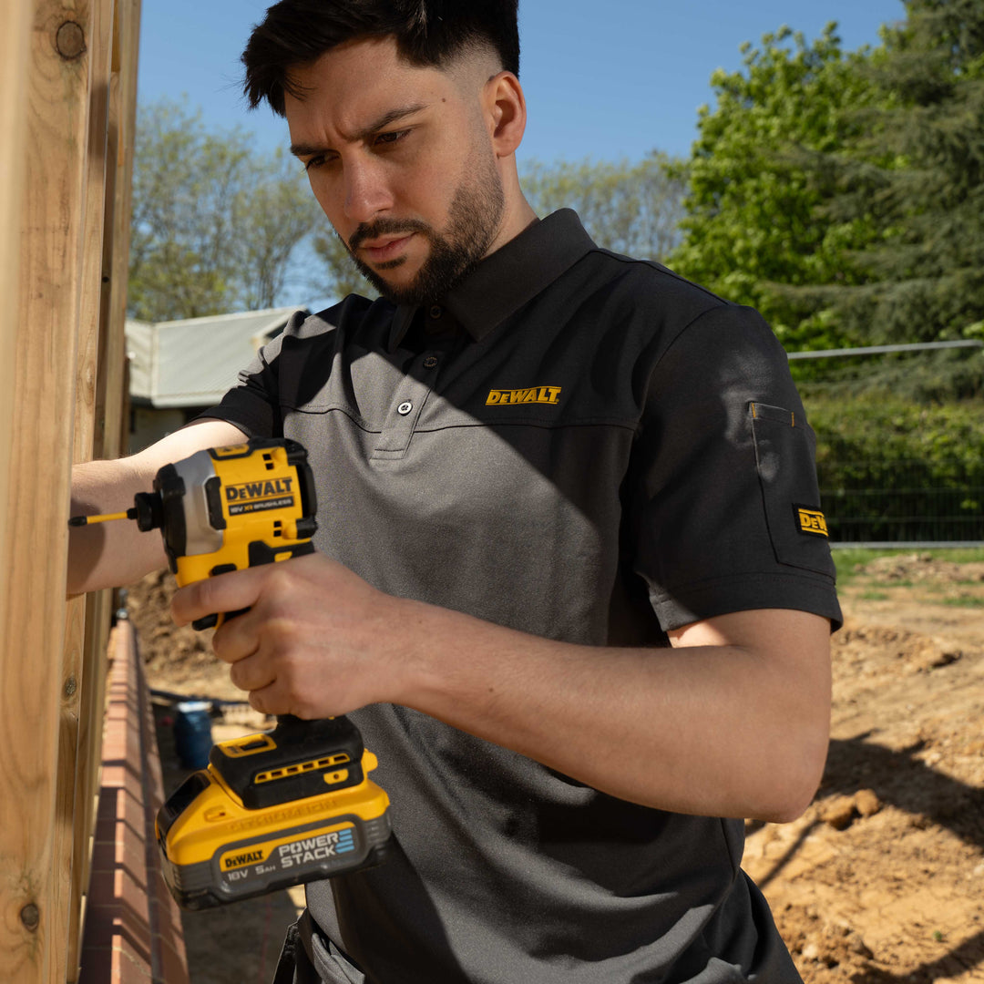 Man using a Dewalt power drill outdoors with trees in the background