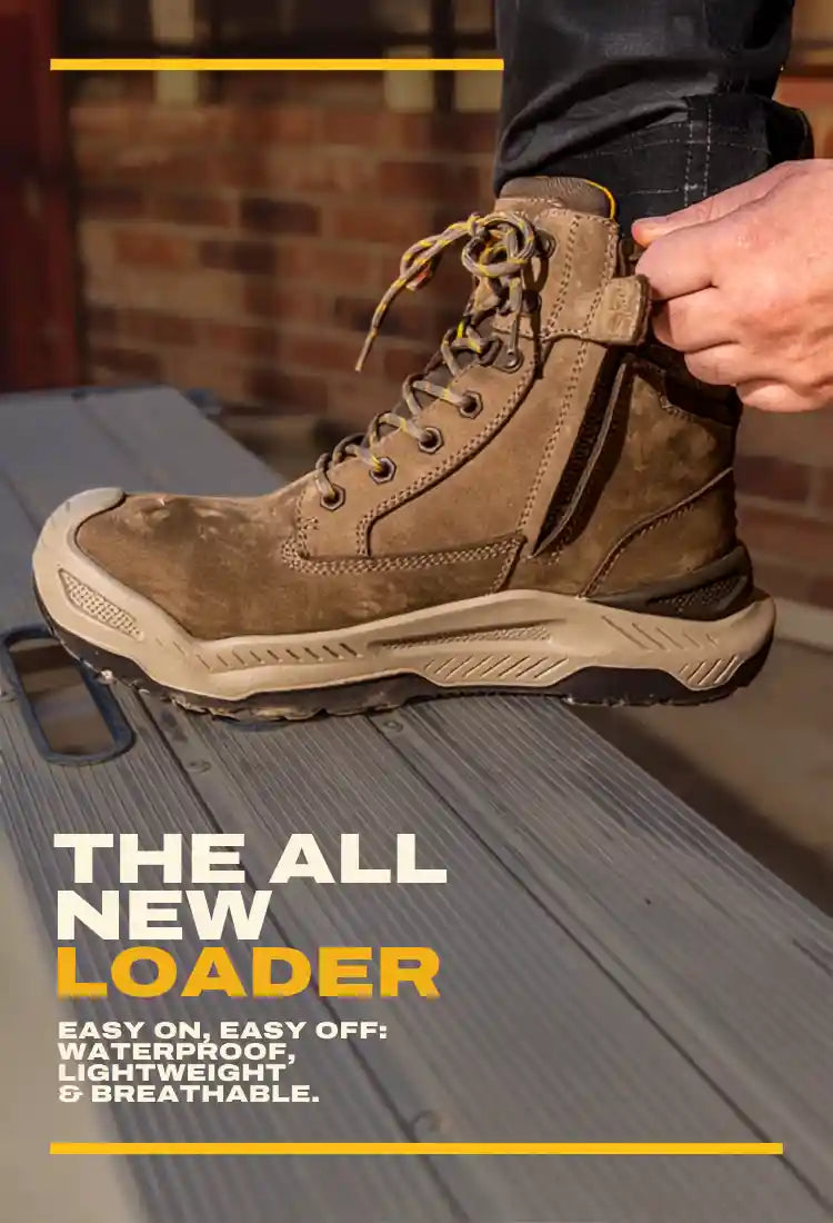 A brown suede lace-up work boot being worn and adjusted by a person's hand, standing on a gray metal surface with promotional text overlay reading 'THE ALL NEW LOADER'.
