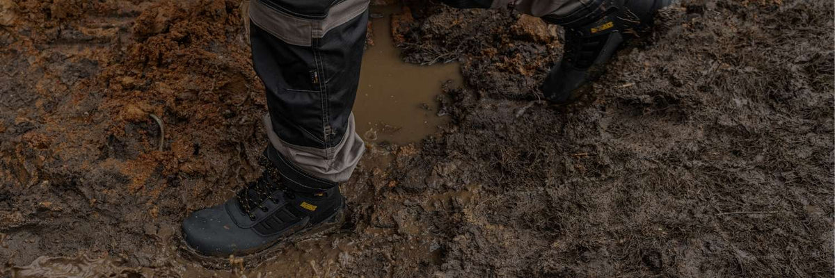 Person wearing work boots walking through a muddy area