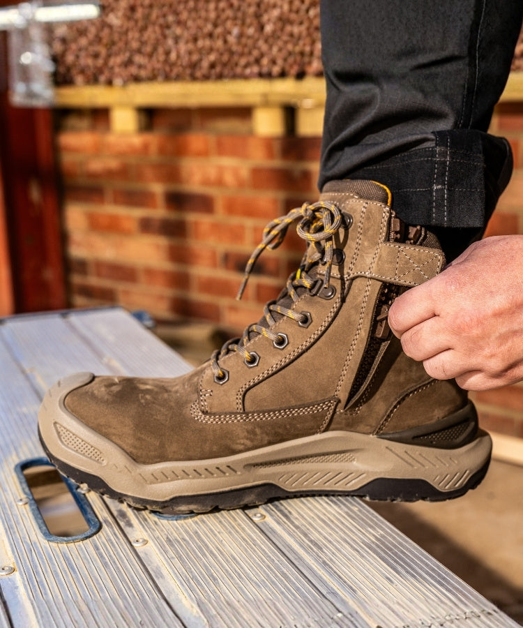Brown work boot being worn on a metal surface with a blurred background